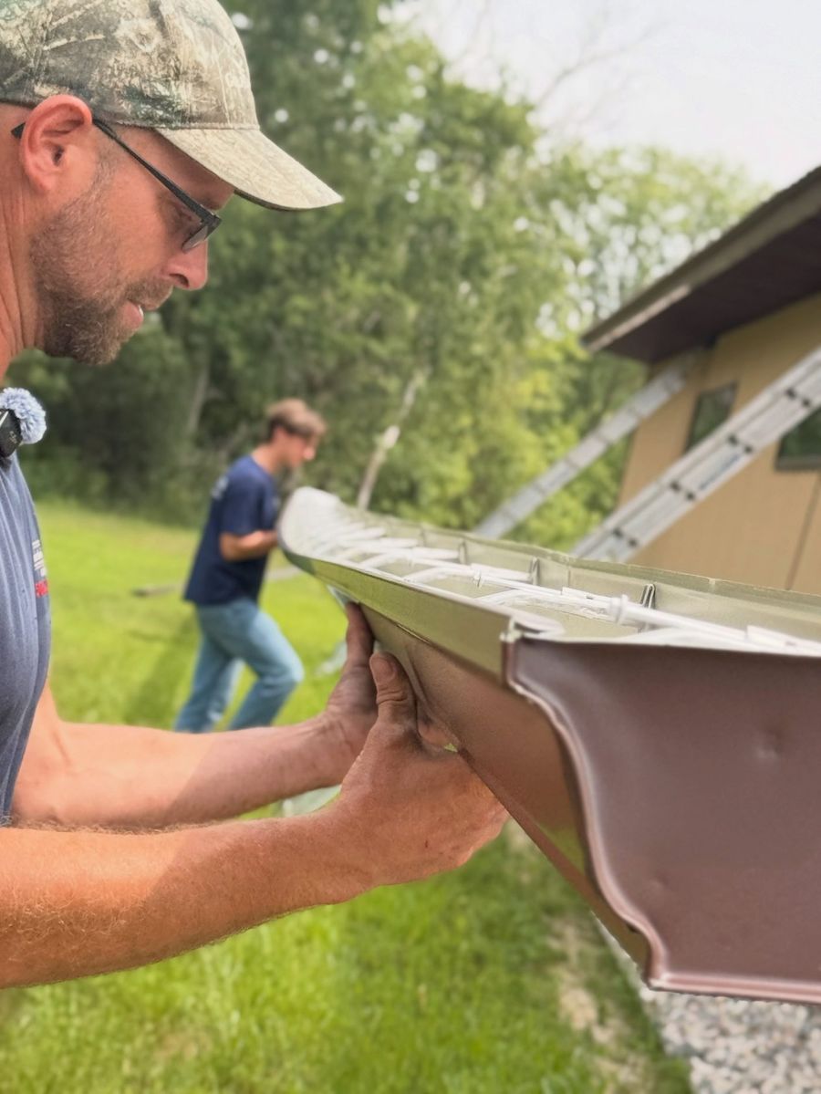 Close-up of hands checking the end cap of a freshly formed brown seamless gutter